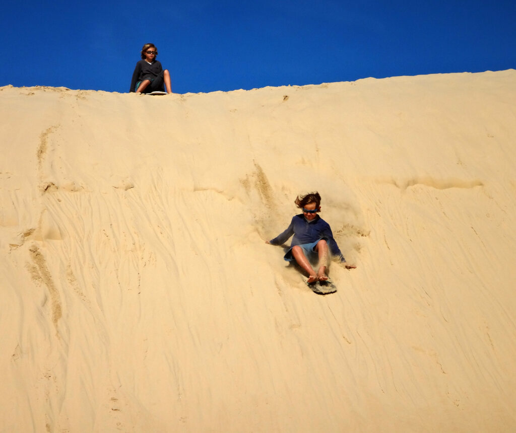 Enfant dévalant une dune de sable en Australie