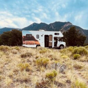 Camping-car garé dans les herbes sèches au pied des montagnes, pendant un roadtrip aux États-Unis